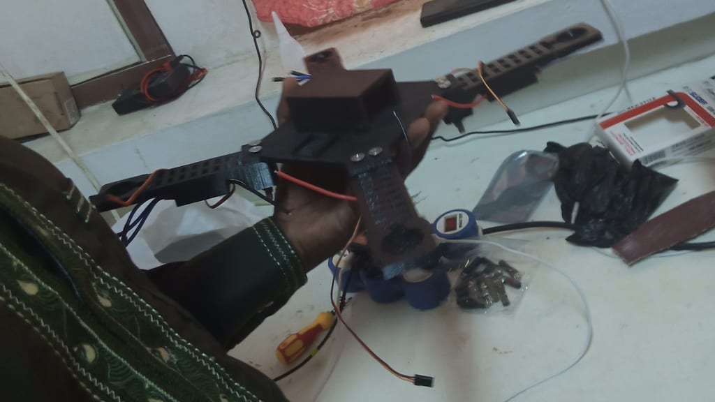 Partially assembled quadcopter held above a workbench during construction